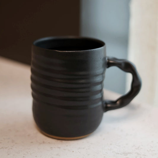Black ceramic mug with a handle on a light surface