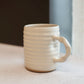 Cream ceramic mug with a handle on a light surface