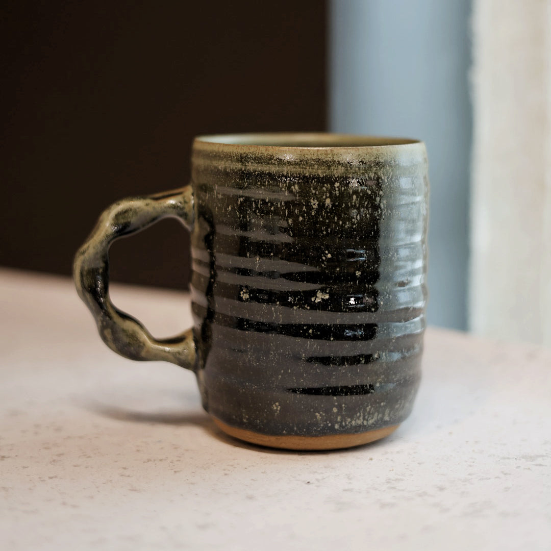 Green ceramic mug with textured surface on a light surface