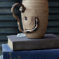 Ceramic mug with a unique handle on top of books