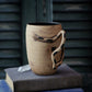 Ceramic mug with a unique handle on top of books against a dark background