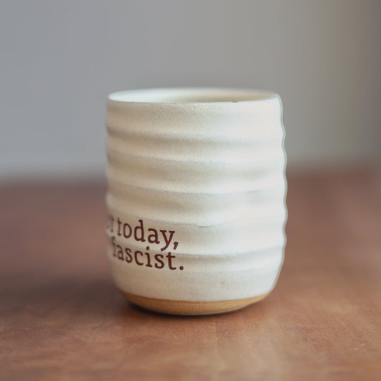 Cream ceramic cup with text on a wooden surface