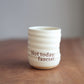 Cream ceramic everyday cup with text 'Not today, fascist' on a wooden surface.