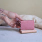 Person holding a small pink bar of soap with a white background