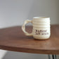 Cream ceramic mug with text on a wooden table that says “radical left scum”