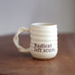 Cream ceramic mug with text on a wooden surface and gray background