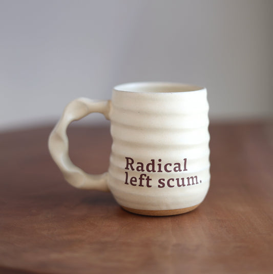 Cream ceramic mug with text on a wooden surface and gray background