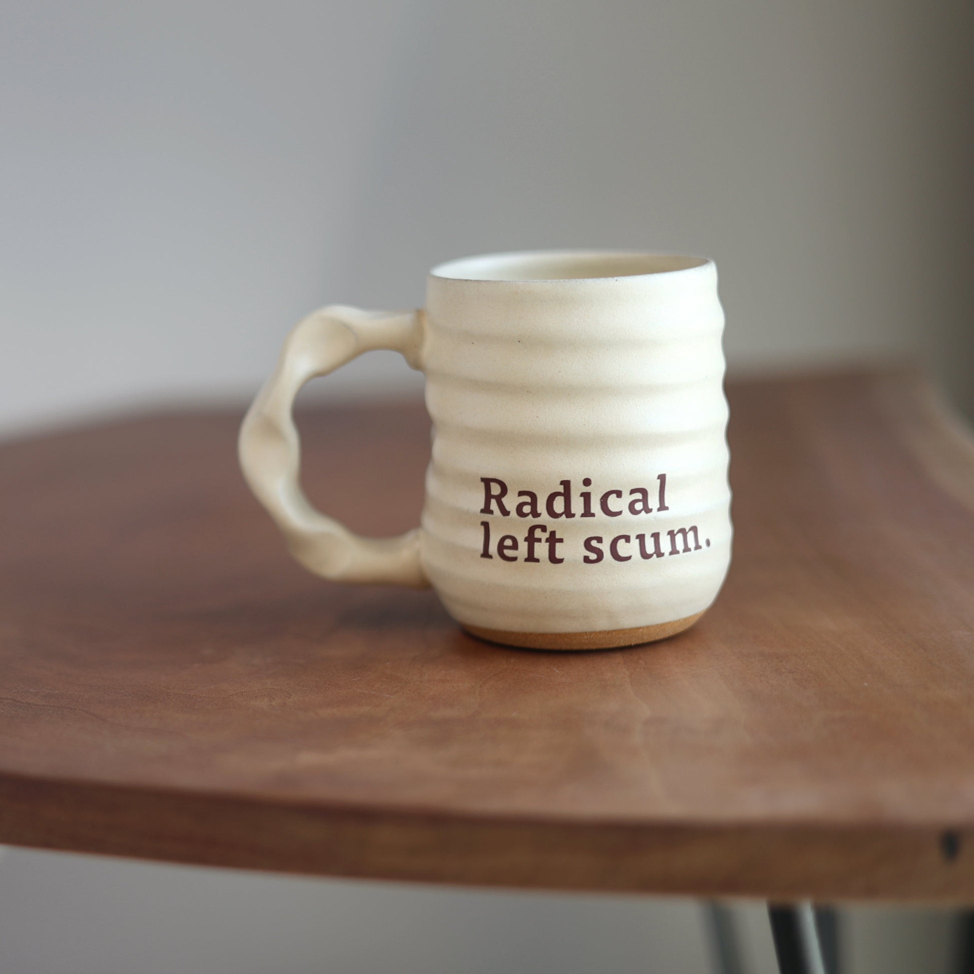 Off white mug with 'Radical left scum' text on a wooden table