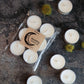 White candles with a Rewilding brand label on a textured surface