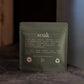 Green package labeled 'soak' on a dark surface with a blurred background