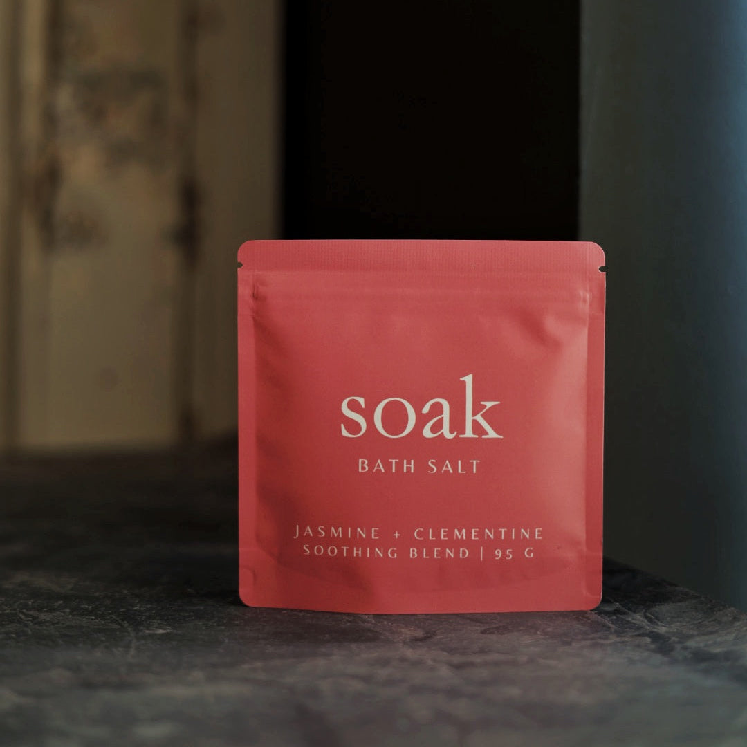 Coral packet of 'soak' bath salt on a dark surface with a blurred background