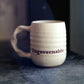 White mug with 'Ungovernable' text on a textured surface with blurred background