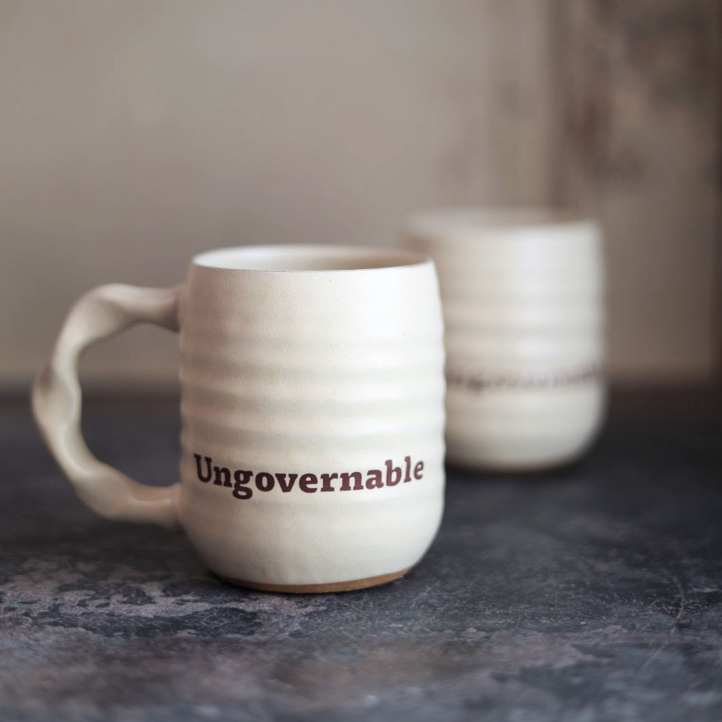 White ceramic mug with 'Ungovernable' text on a dark surface