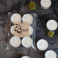 Packaged and unpackaged pure soy candles on a textured surface with a visible brand label.