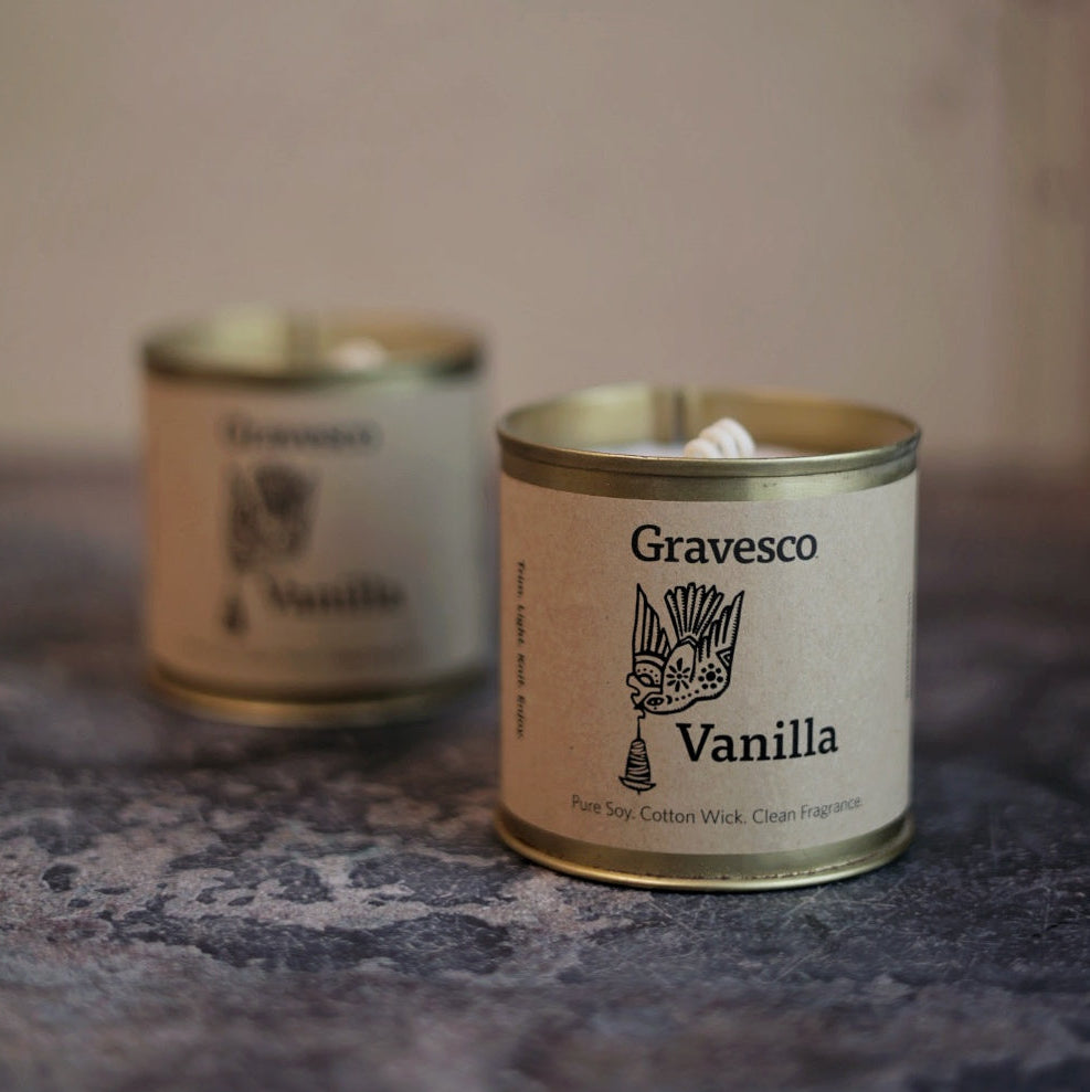 Two candles with 'Gravesco Vanilla' label on a textured surface.