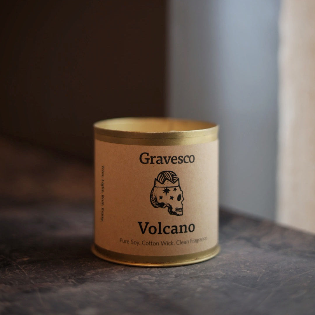 Candle labeled 'Gravesco Volcano' on a dark surface with a blurred background