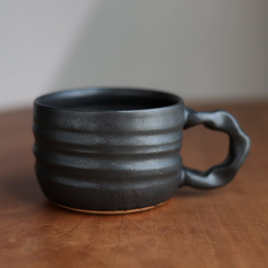 Black ceramic mug with handle on a wooden surface