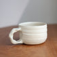 White ceramic cup with handle on a wooden surface