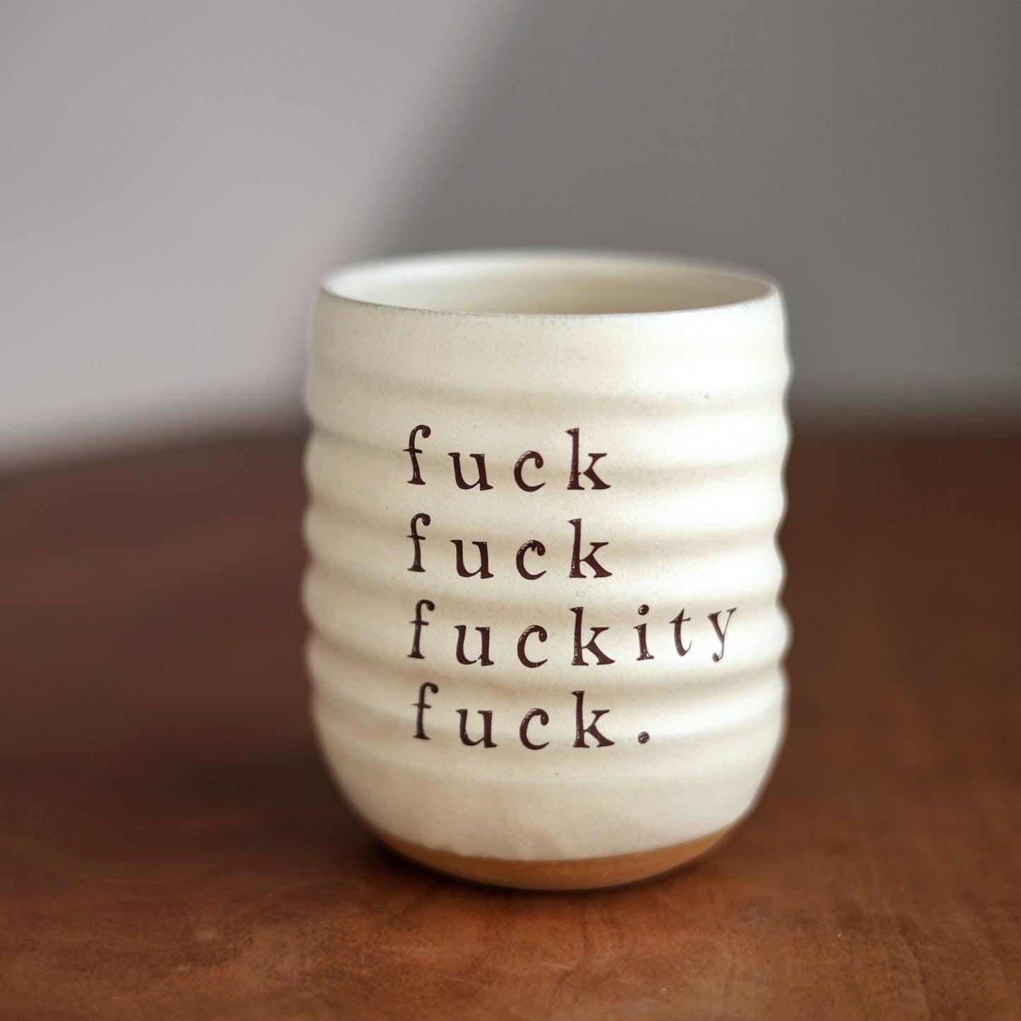 White ceramic mug with black text on a wooden surface